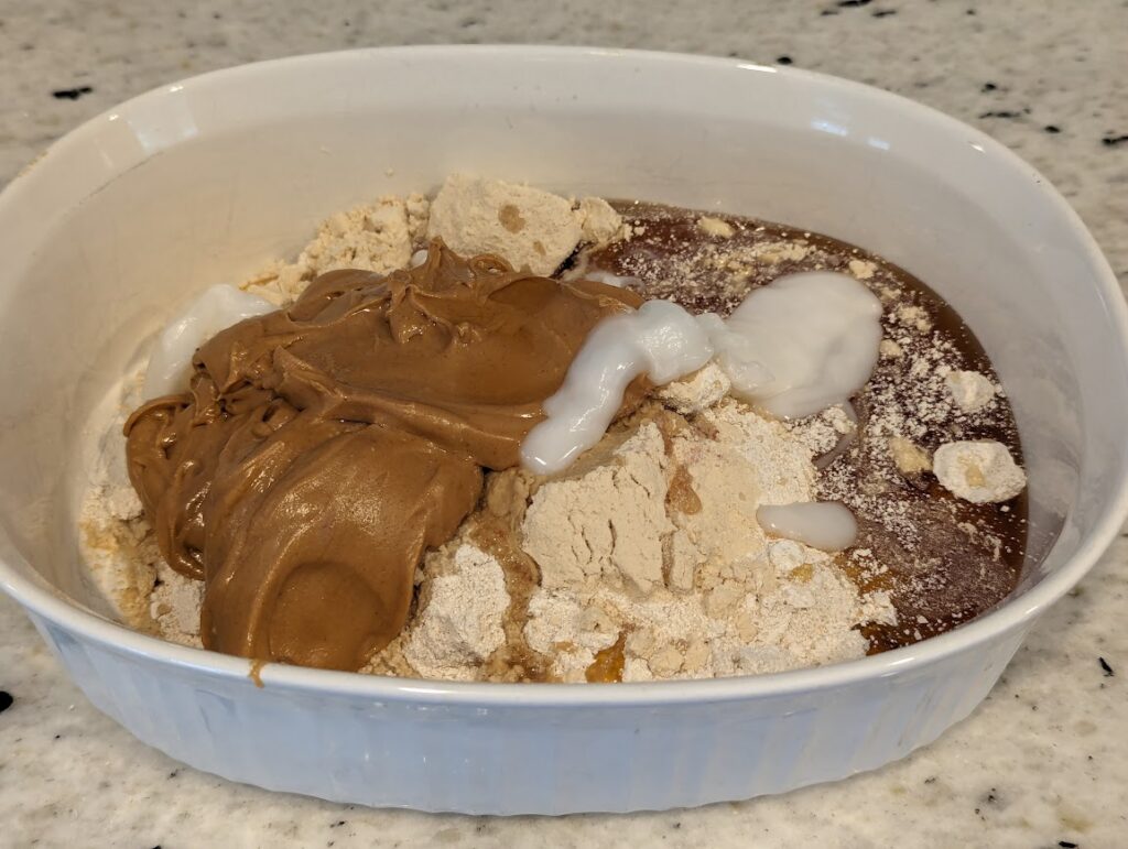 White baking dish with homemade perfect bar ingredients dumped in