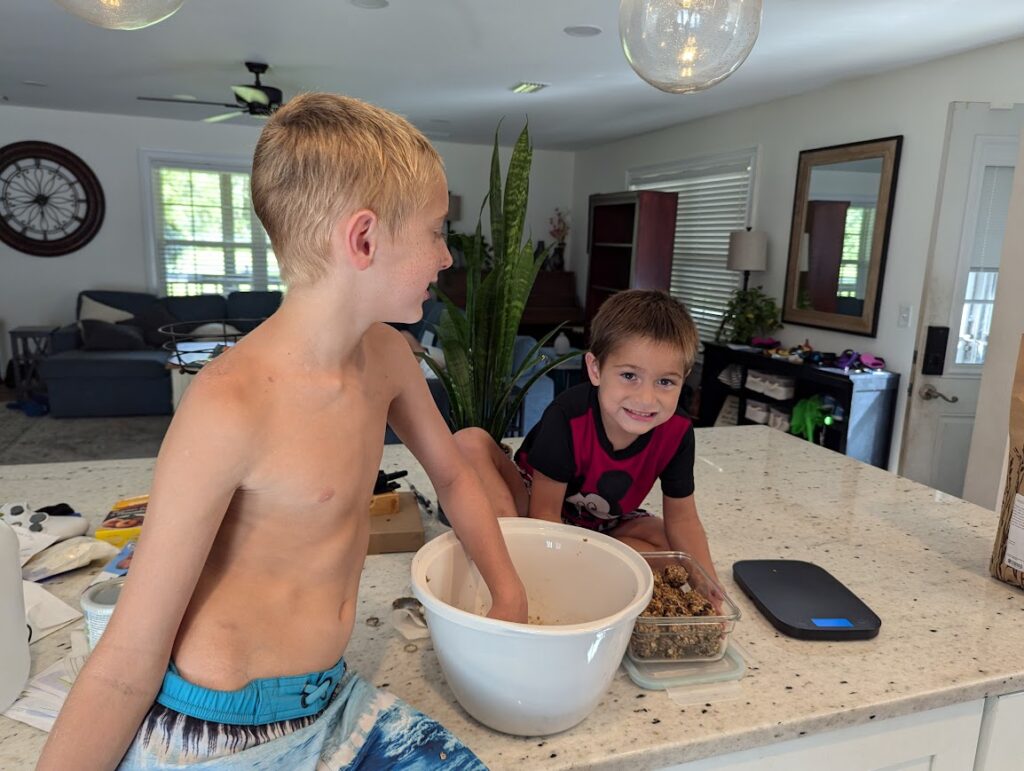 2 boys helping cook Coconut Chocolate Energy Bites at the kitchen island