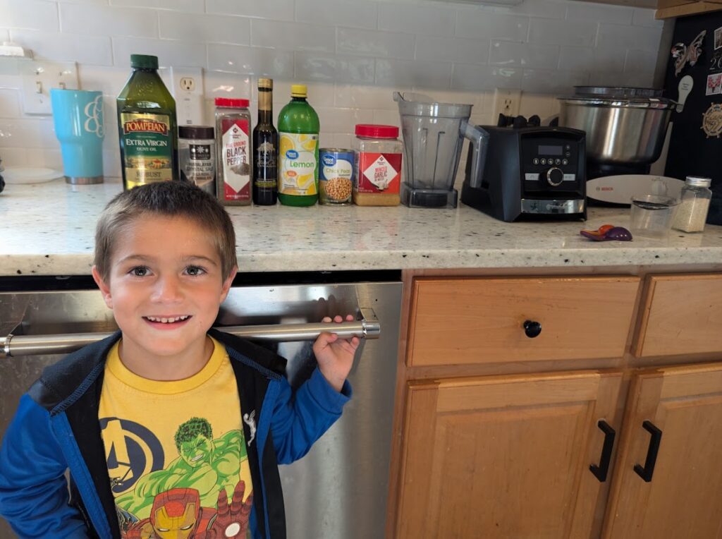 Child standing in kitchen in front of hummus recipe ingredients