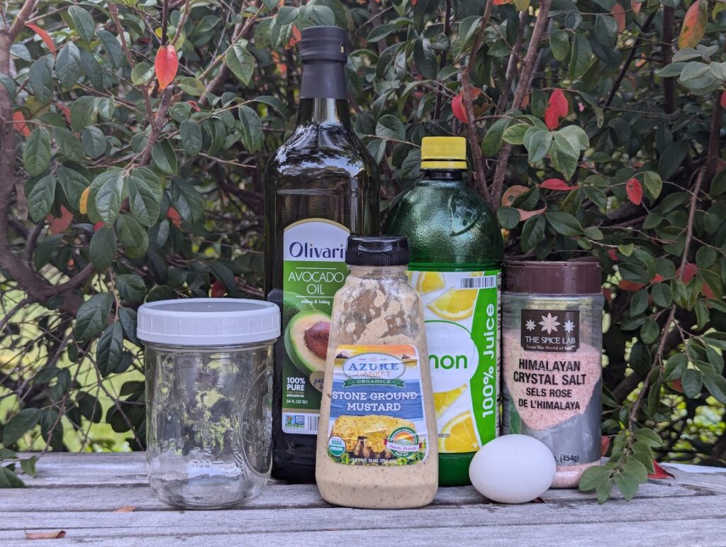 Easy Homemade Mayonnaise Ingredients on table: salt, egg, lemon juice, dijon mustard, avocado oil, and mason jar