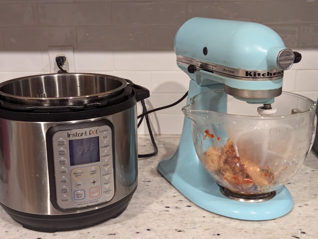 Chicken in Kitchen Aid to be shredded and instant pot next to it on counter