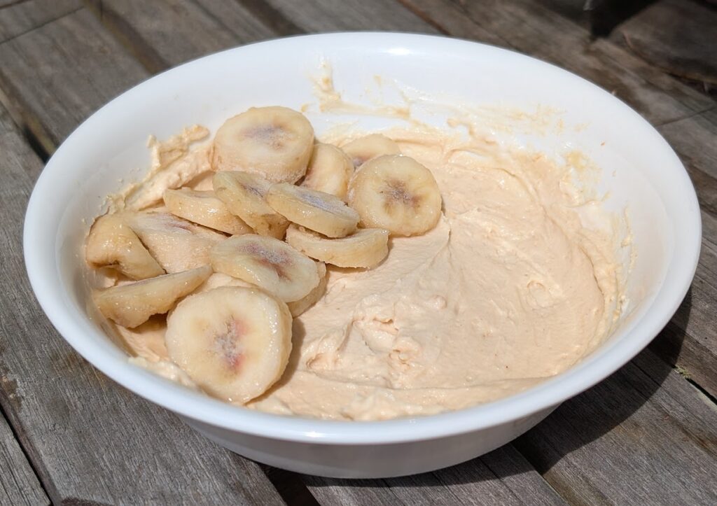 Bananas and peanut butter powder are one idea of what to add to a yogurt bowl